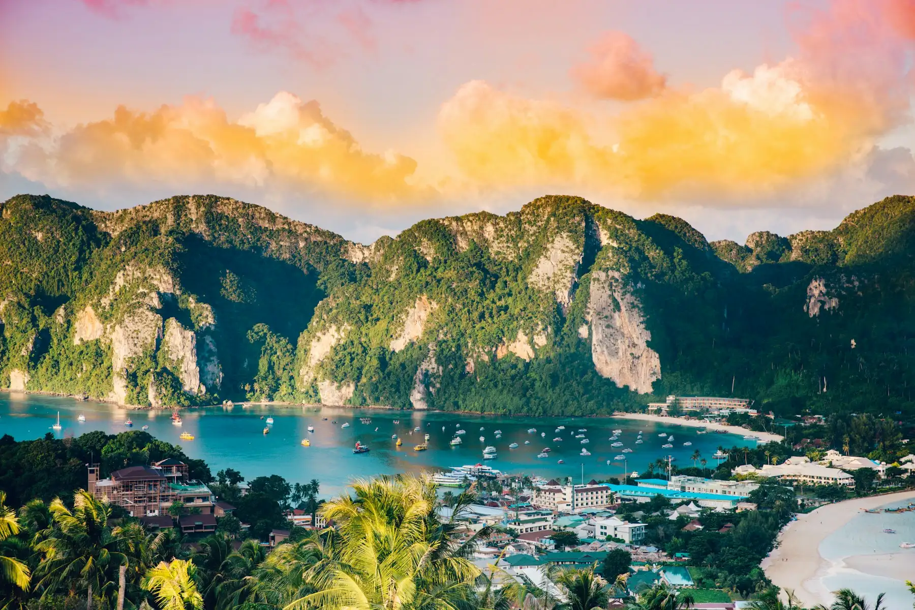 Phi Phi Don seen from the viewpoint, with boats in the bay below green cliffs at sunset